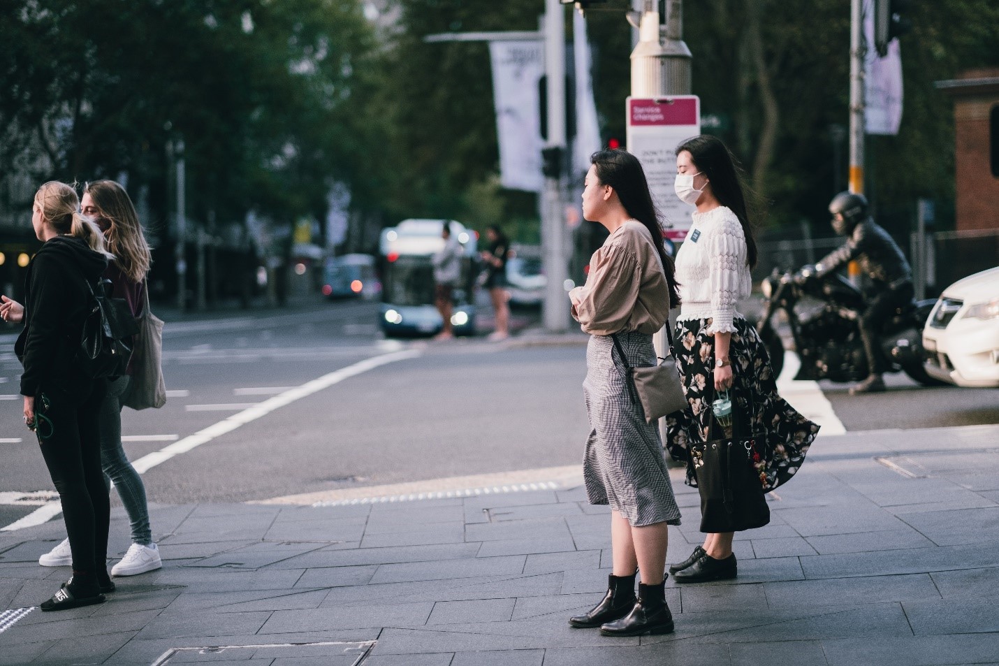 Two women in face masks waiting to cross the street