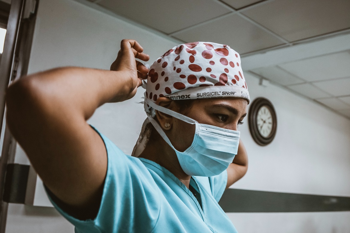 Healthcare worker in PPE tying mask on