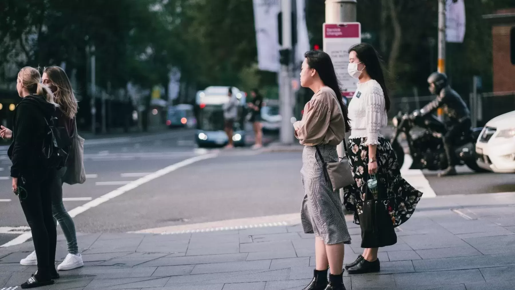 Two women in face masks waiting to cross the street