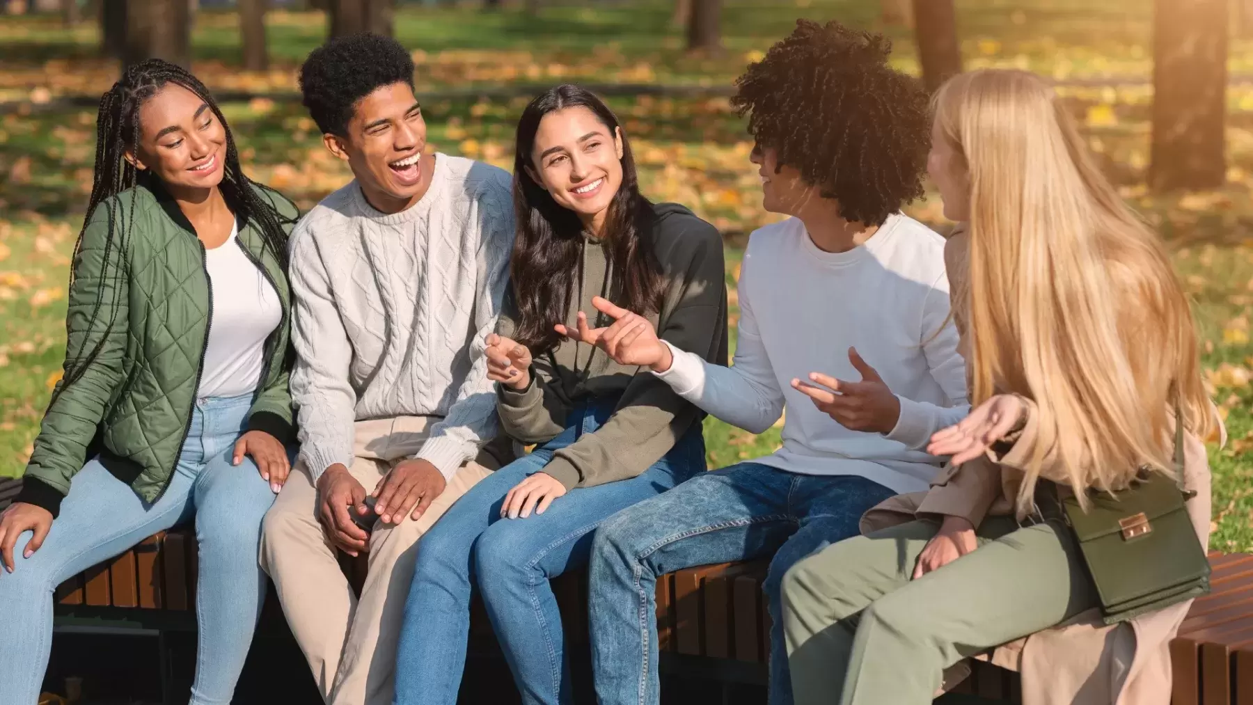 youth sit together on a bench talking animatedly and smiling