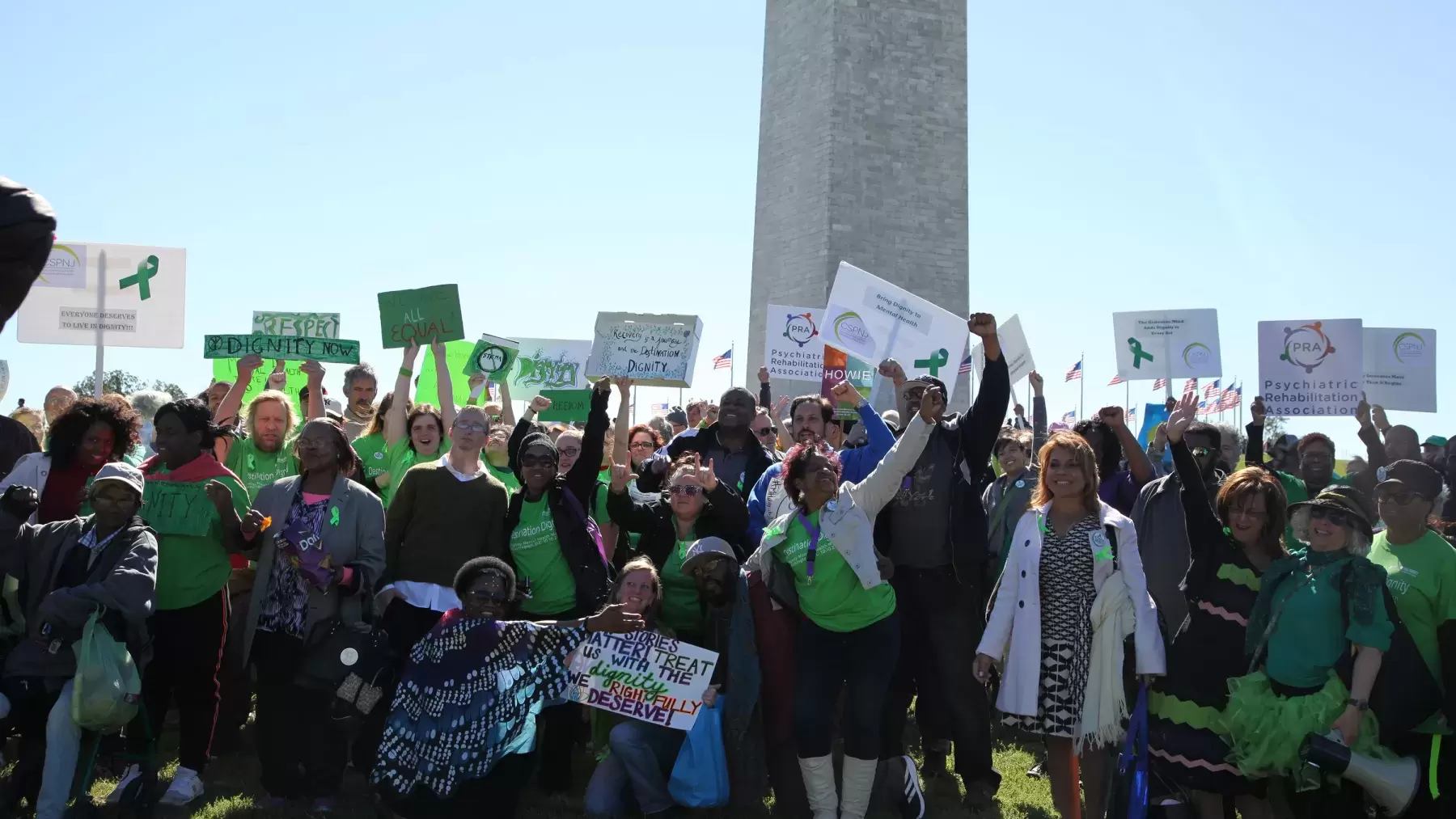 group of people in lots of light green shirts carrying posters and placards in front of Washington Monument