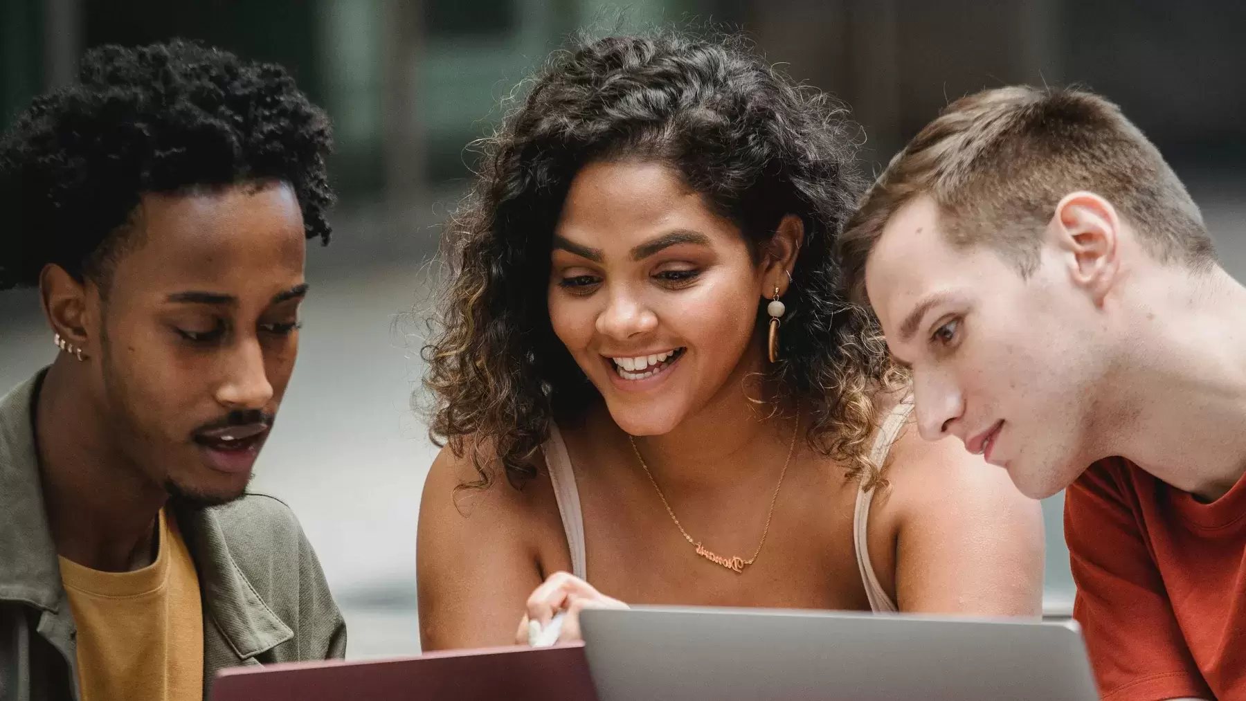 college students looking at a laptop and working together