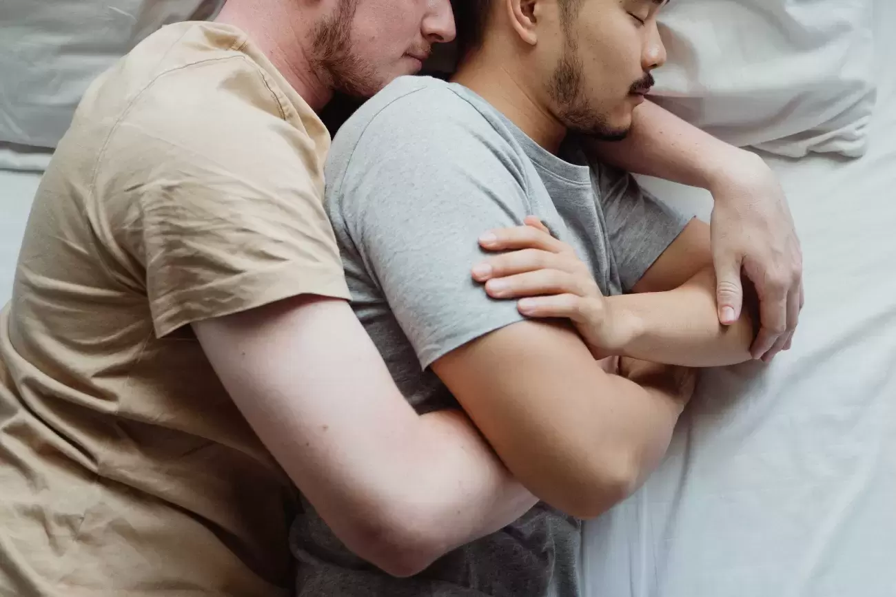 two people cuddle each other in a bed while sleeping