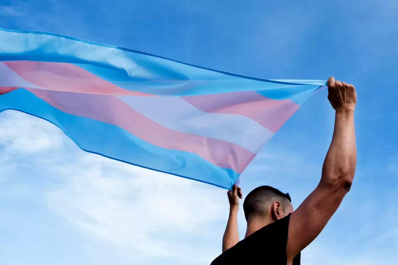 person carries transgender flag streaming behind them