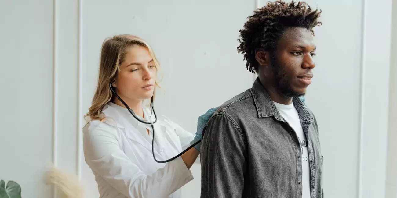 doctor listens to patient's back with stethoscope