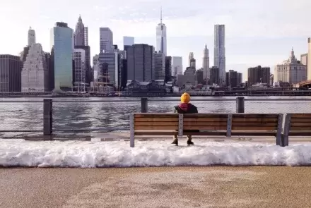 man on bench staring across lake in winter