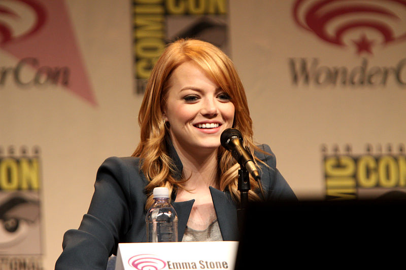 Emma Stone is seated at a microphone and is smiling